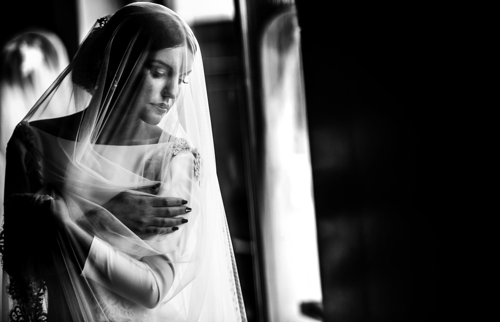 Una foto espectacular de la novia en blanco y negro, con el velo por delante.