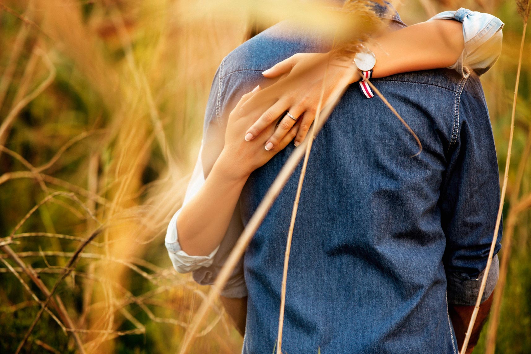 La novia abrazada a su novio y donde se puede ver su anillo de compromiso.